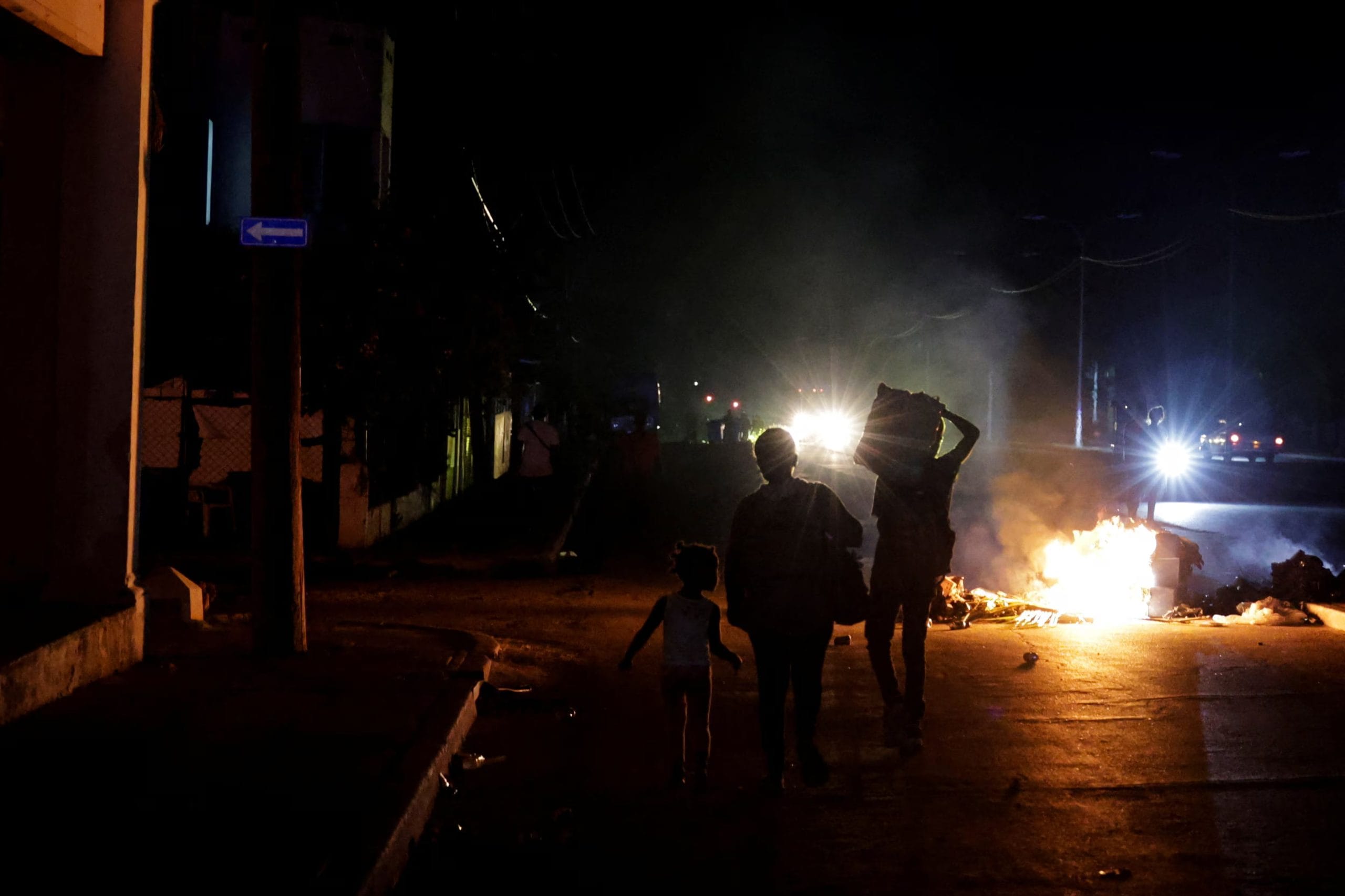Un grupo de personas pasa junto a la basura prendida fuego en medio de una calle durante una protesta contra los frecuentes cortes de electricidad en La Habana, Cuba. 13 de mayo de 2026 (REUTERS/Norlys Pérez)