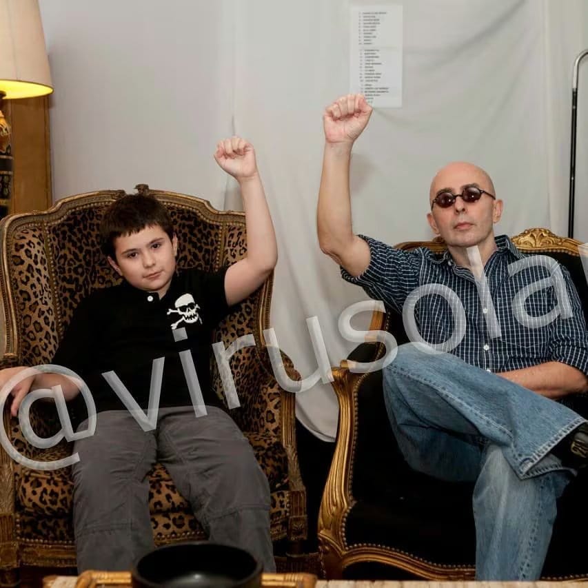 Indio Solari y su hijo posan juntos, ambos levantando el puño cerrado en señal de unidad y resistencia.