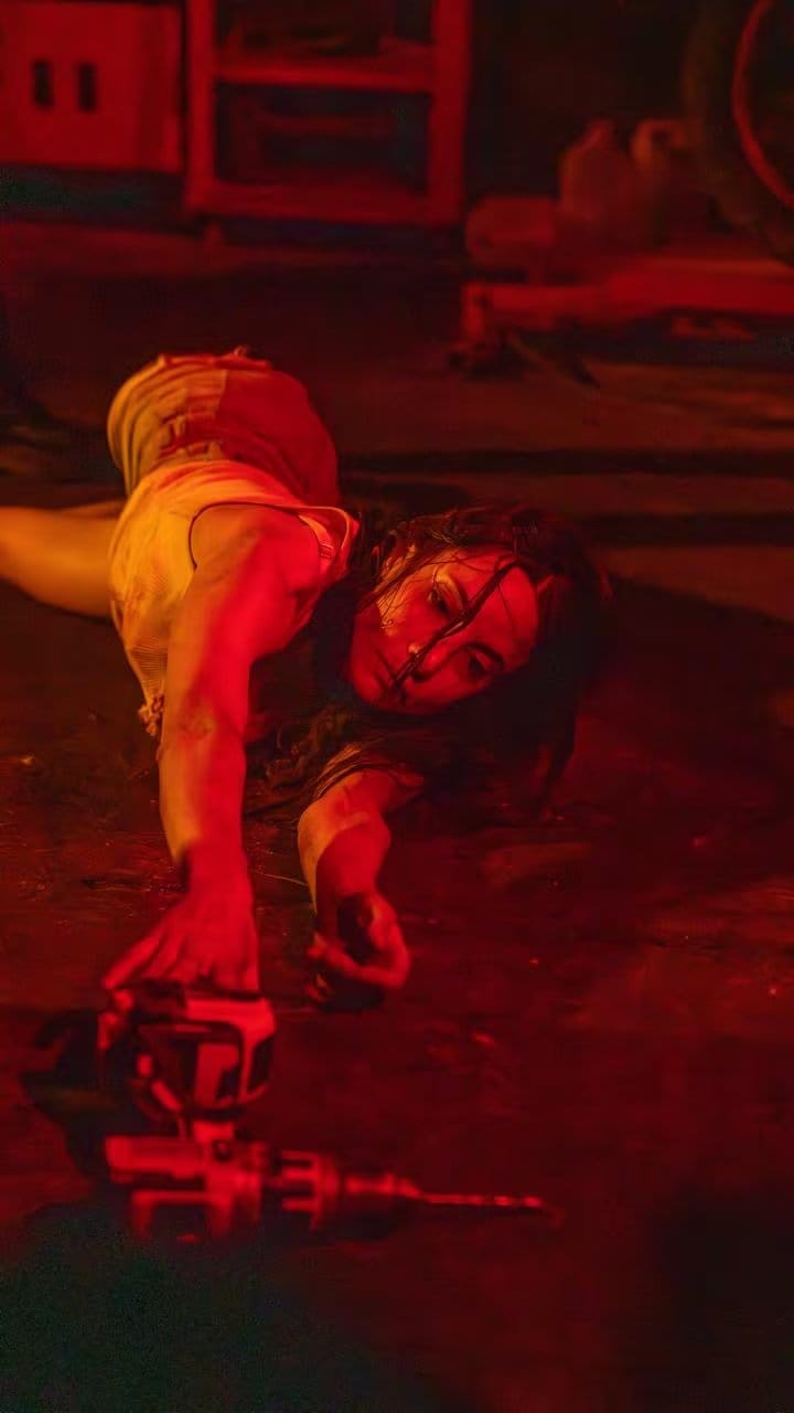 Magui Bravi aparece angustiada en una escena de 'Hotline', bajo una luz roja mientras extiende la mano hacia un taladro.