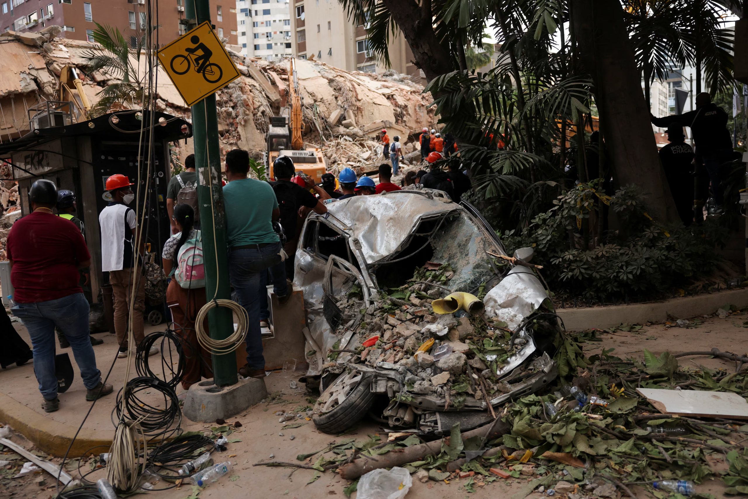 Varias personas se encuentran junto a un coche siniestrado, cerca de los escombros de un edificio derrumbado, tras los terremotos ocurridos en Caracas, Venezuela, el 25 de junio de 2026 (REUTERS/Leonardo Fernández Viloria)