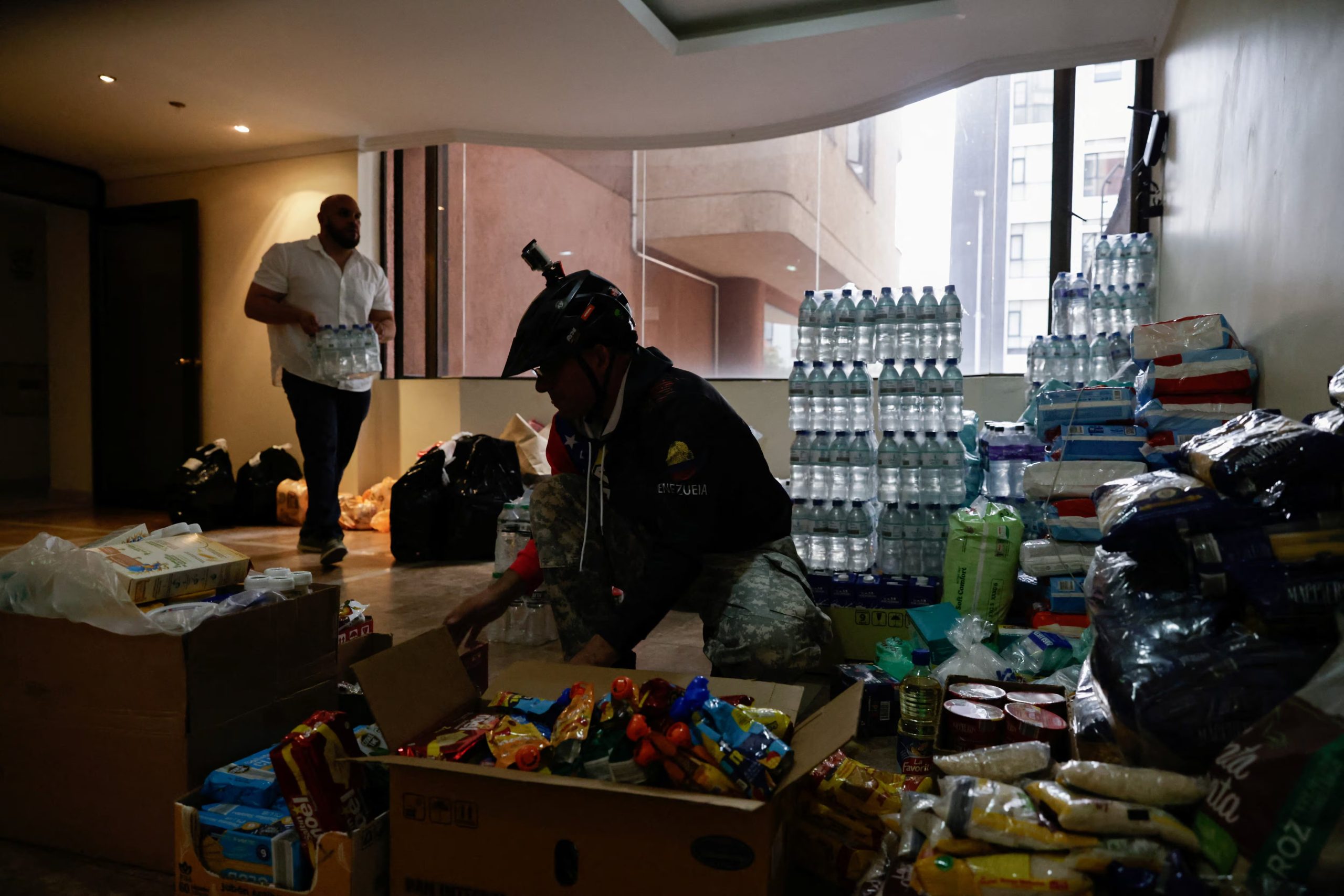 Migrantes venezolanos reciben y clasifican alimentos, medicamentos y suministros de ayuda humanitaria que se enviarán a las comunidades afectadas por los recientes terremotos en Venezuela, en un centro de recogida improvisado en Quito (Ecuador), el 25 de junio de 2026 (REUTERS/Karen Toro)
