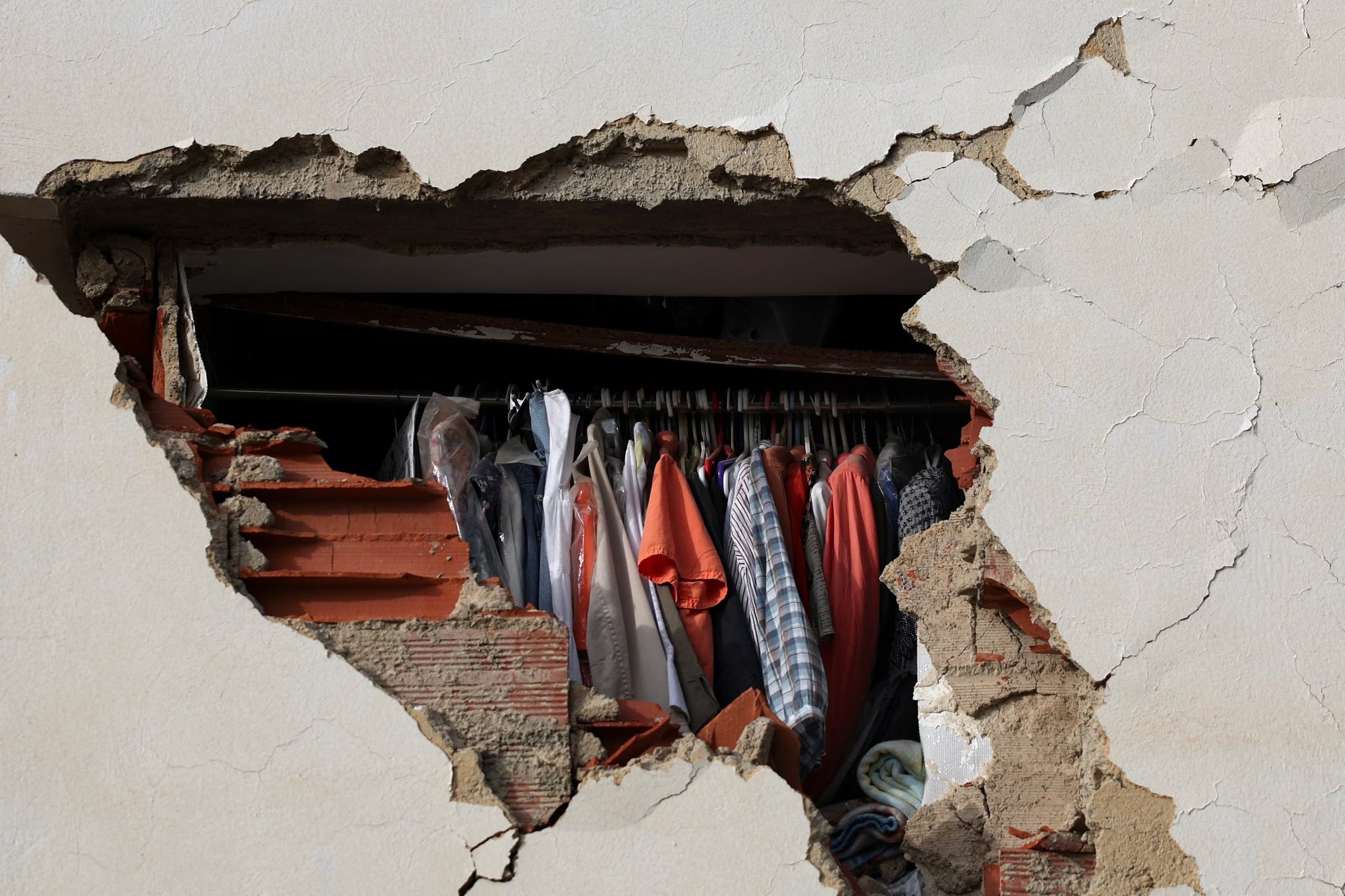 Prendas de vestir dentro de un armario se asoman a través de un boquete en la pared de un edificio colapsado en La Guaira, la zona más afectada tras el doble terremoto del 24 de junio. (REUTERS/Pablo Sanhueza)