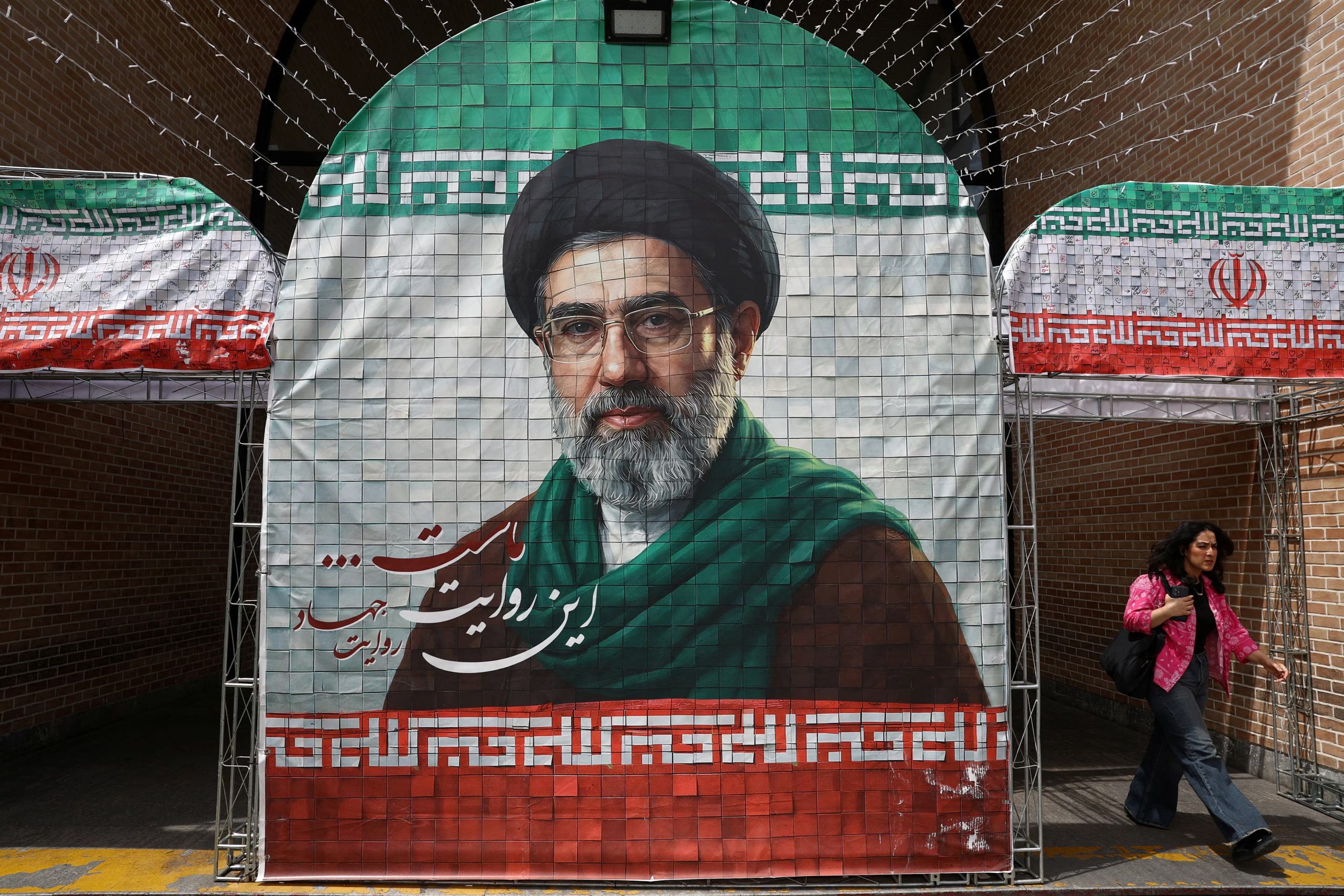 Una mujer camina junto a una pancarta con la imagen del nuevo líder supremo de Irán, Mojtaba Jamenei, en Teherán, Irán, el 8 de mayo de 2026 (WANA vía REUTERS)