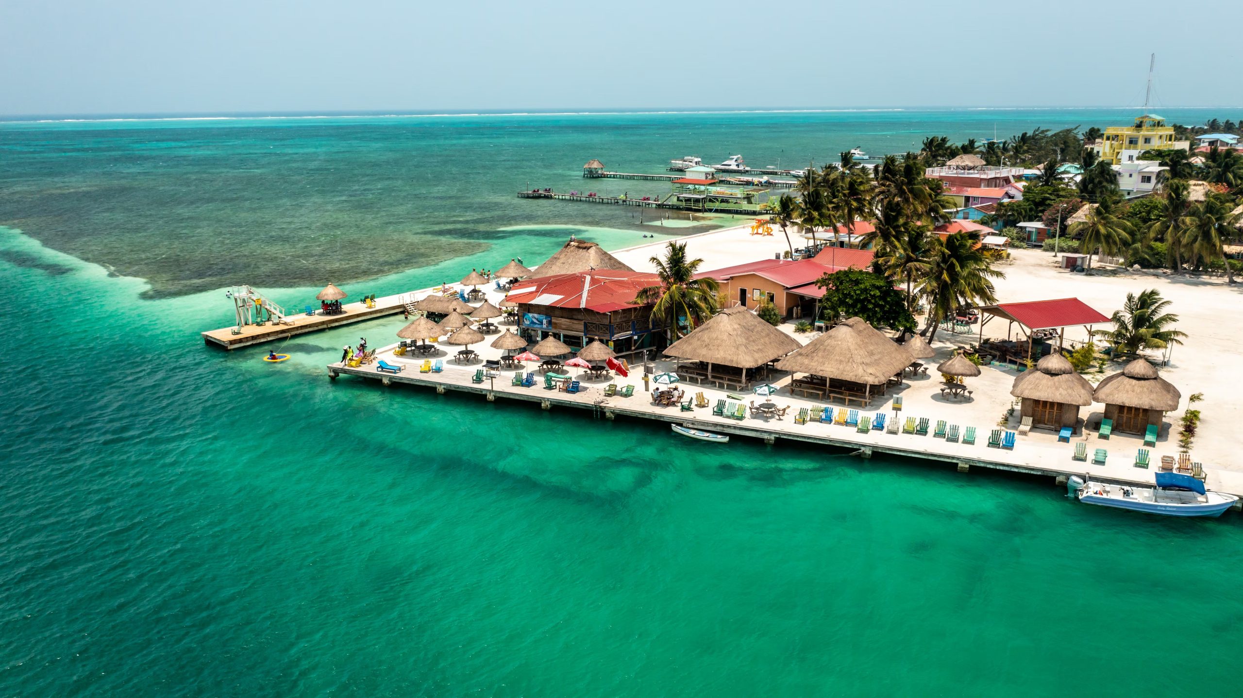 Una panor&aacute;mica a&eacute;rea muestra el Sea Crest Oceanfront Resort con sus estructuras de techo de paja, muelles, embarcaciones y aguas cristalinas en Caye Caulker. (The Belize Tourism Board (BTB), &oacute;rgano del Ministerio de Turismo y Relaciones con la Di&aacute;spora de Belice.)