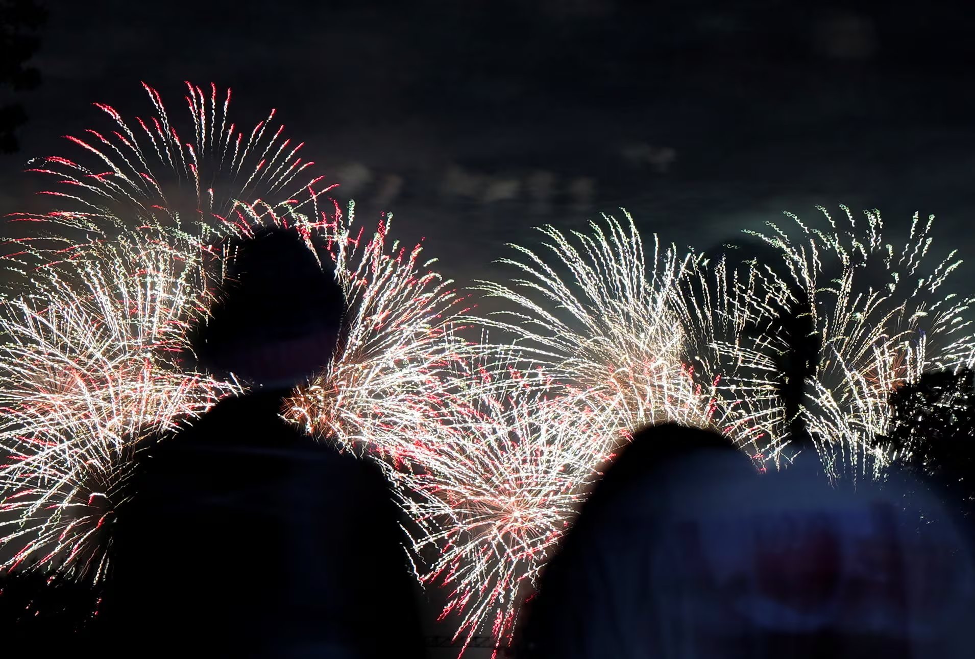 Personas observan la explosi&oacute;n de fuegos artificiales durante el evento 