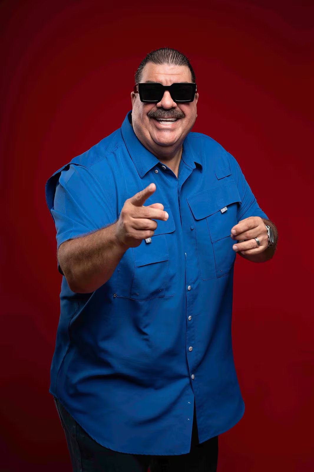 El cantante Maelo Ruiz posa con gafas de sol y camisa azul, señalando con su dedo al frente, previo a su presentación en el Salsa Lima Festival de Perú.