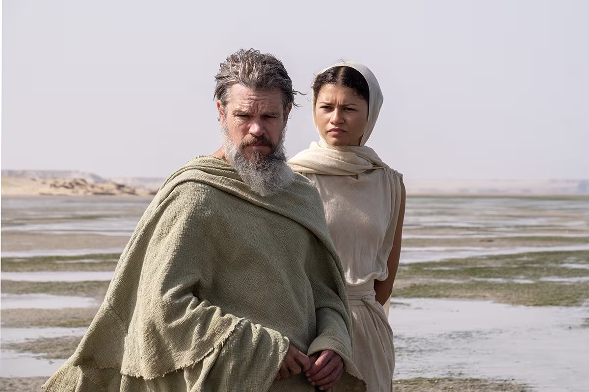 Zendaya y un actor, caracterizados con vestuario de &eacute;poca, se sit&uacute;an en un vasto paisaje des&eacute;rtico que simula un entorno antiguo para la producci&oacute;n de The Odyssey. (Foto: Universal Pictures)